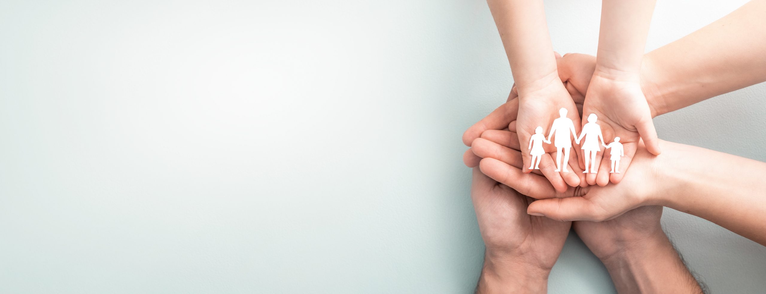 Hands with cut out paper silhouette on table. Family care concept.